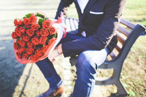 The picture shows a man holding a branch of red roses