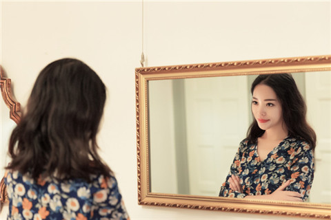 The picture shows a pretty girl is looking in the mirror