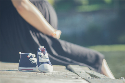 The picture shows a pregnant woman and baby shoes